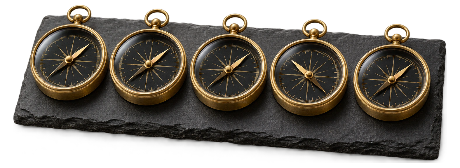 Five brass compasses on slate. Four needles point the same way, the needle of the fourth compass clearly another way.